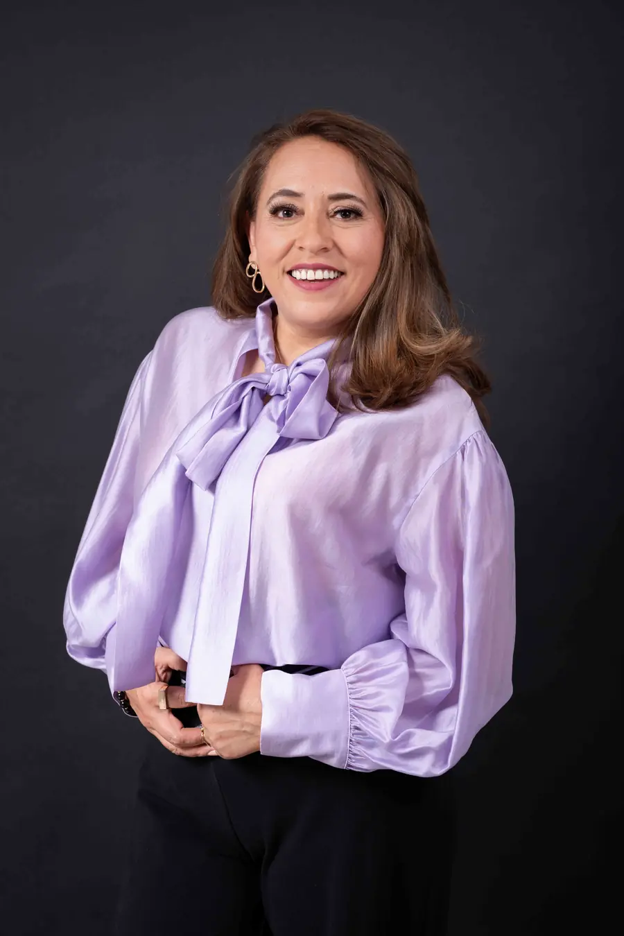 Ely González sonriendo, con blusa lila y moño