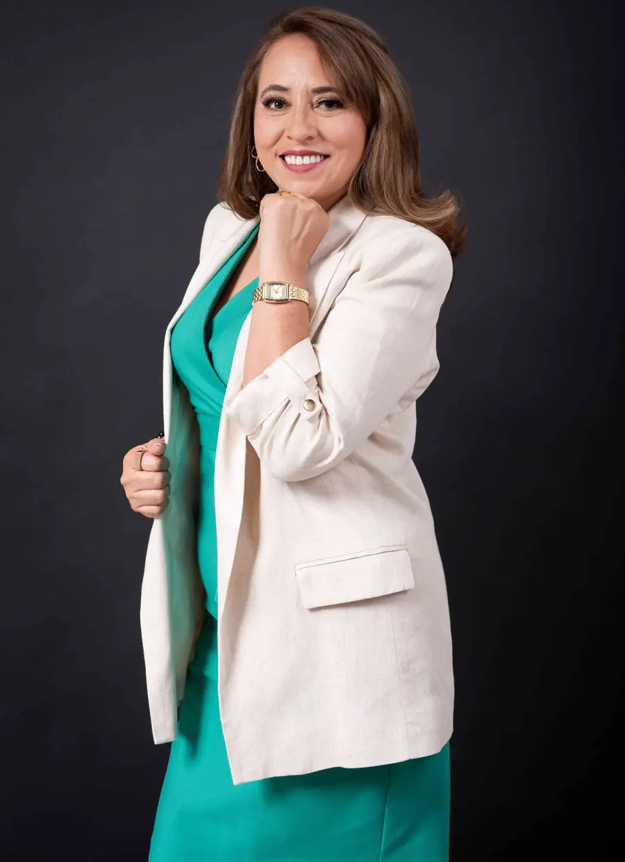 Ely González con blazer beige sobre vestido verde esmeralda