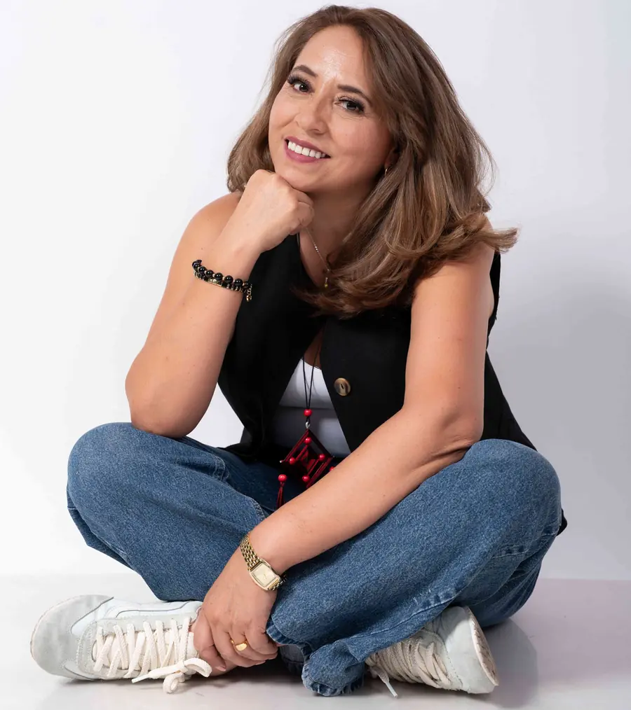 Ely González sentada en el suelo, sonriendo con la mano en la barbilla